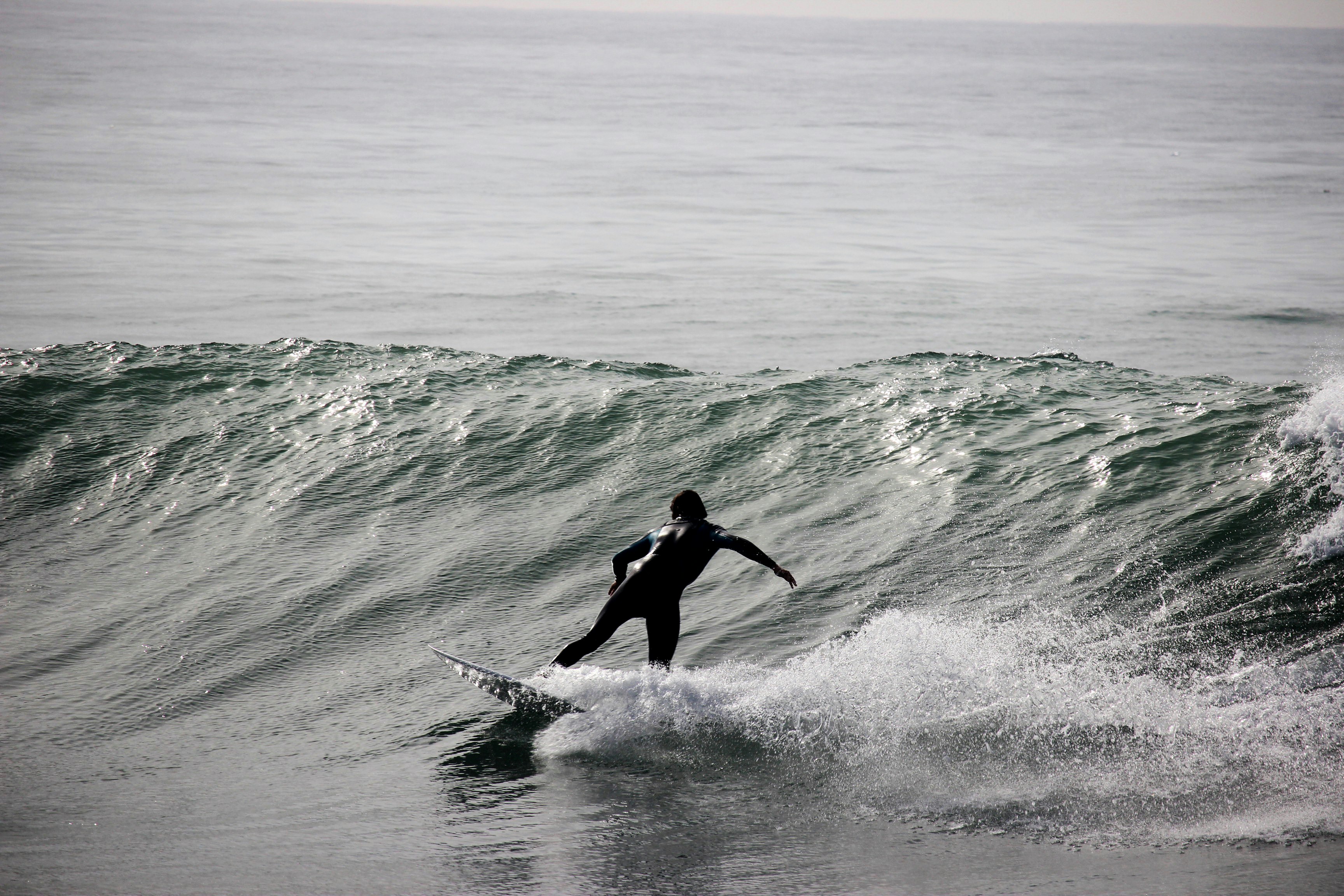 grayscale photography of surfer on body of water during daytime